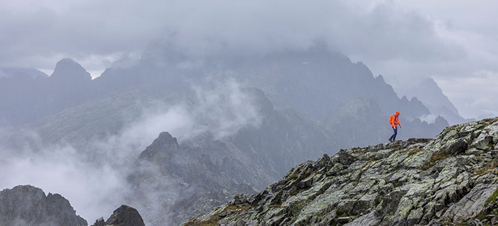 man loopt in de bergen met grauwe wolken om hen heen