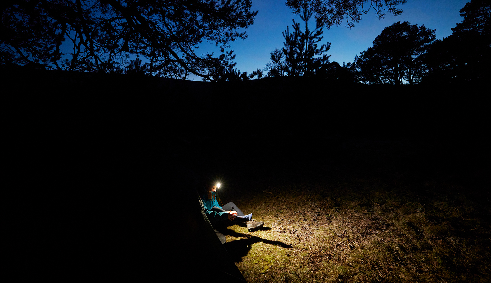 man zit buiten in donker met hoofdlampje 