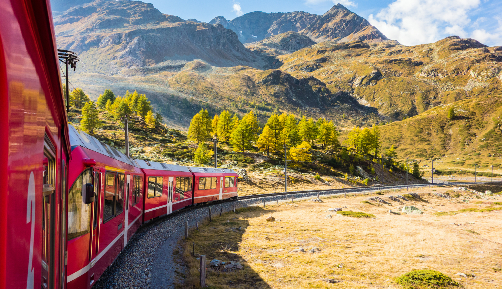 Een rode trein rijdt door een bergachtig landschap
