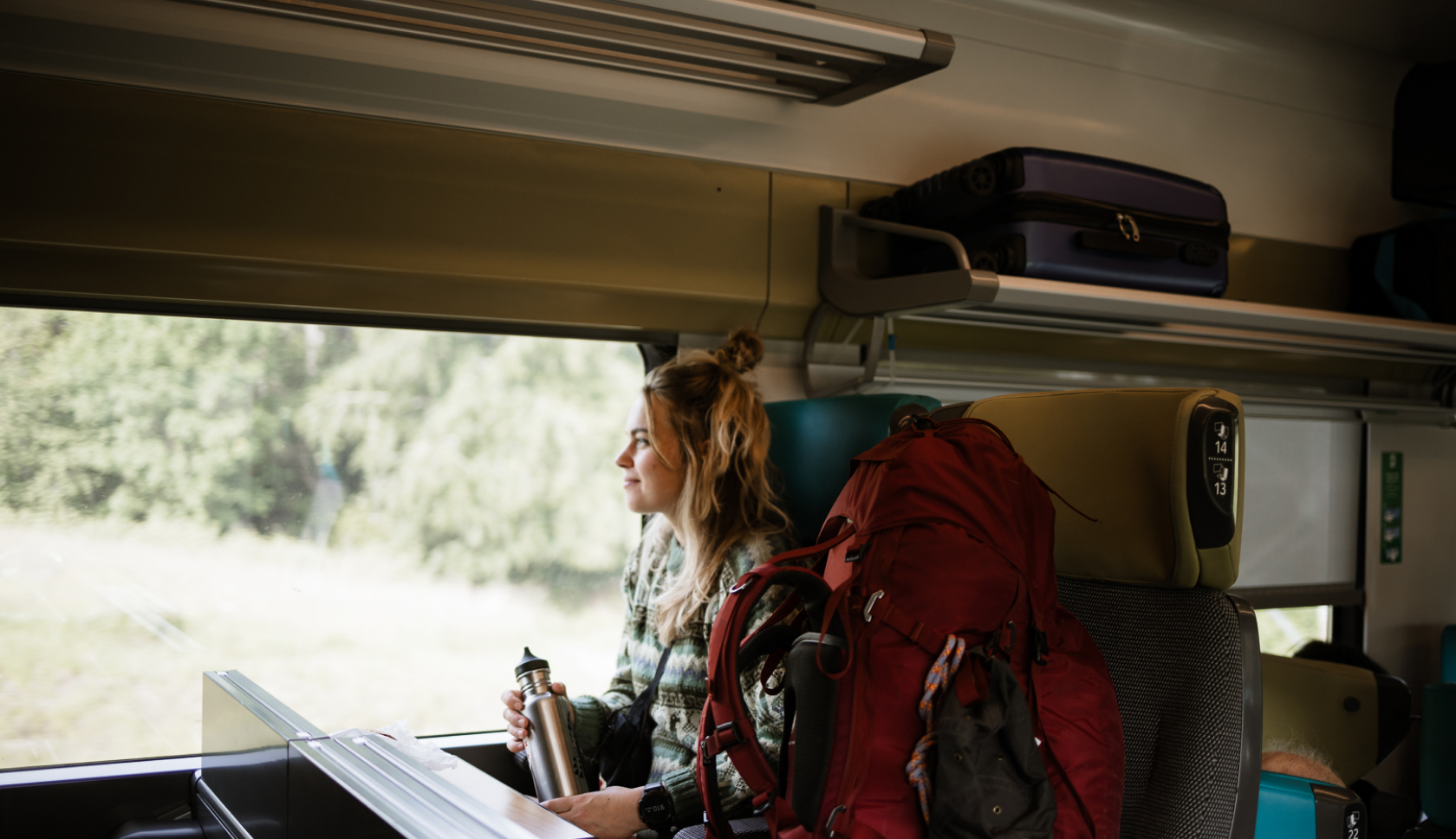 Een backpacker kijkt uit het raam van een trein.