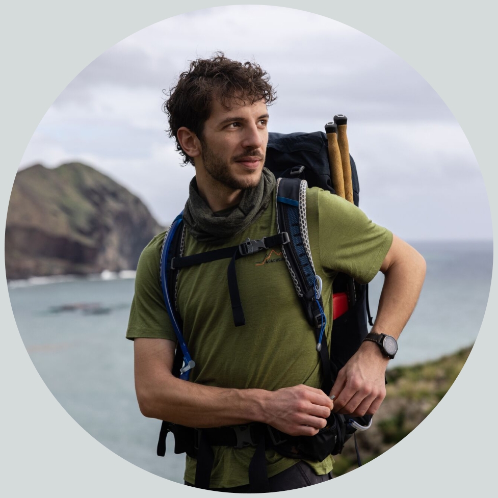 Een man staat in de bergen bij zee