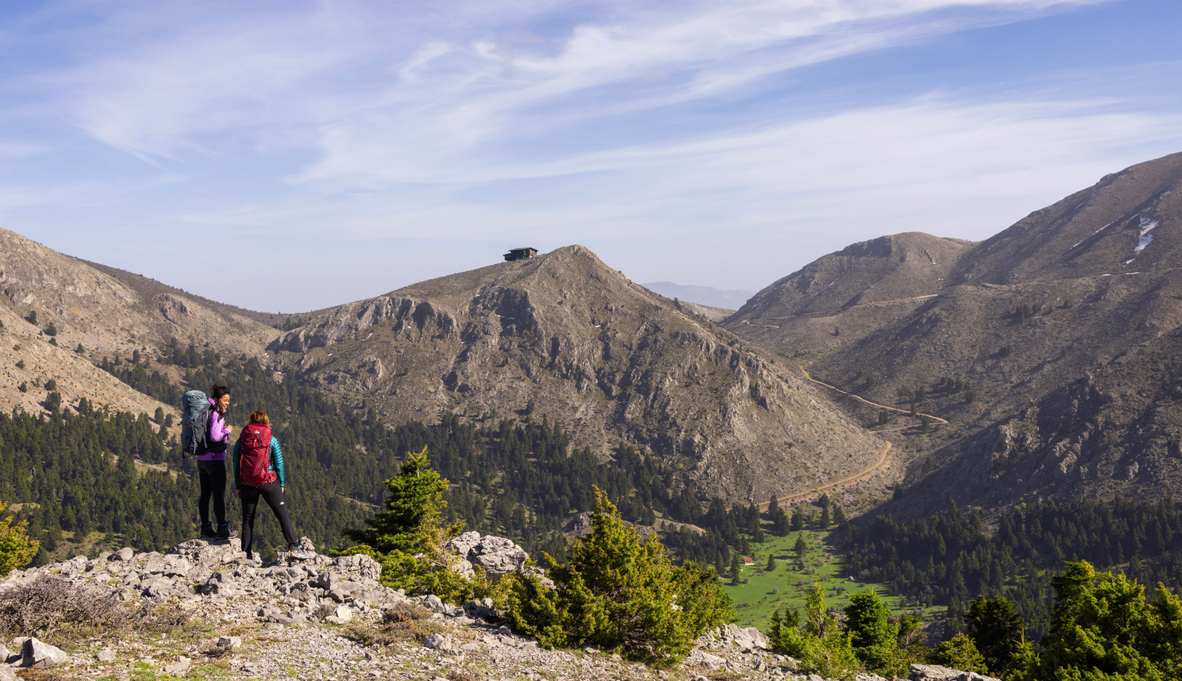 Twee vrouwen met backpacks kijken naar een vallei in de bergen