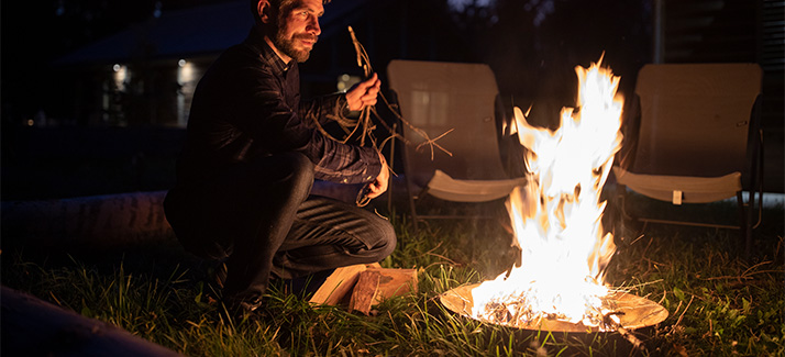 kampeerder zit in het gras bij een kampvuur