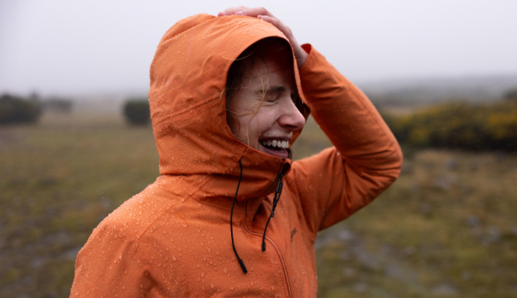 vrouw draagt een oranje regenjas in de regen