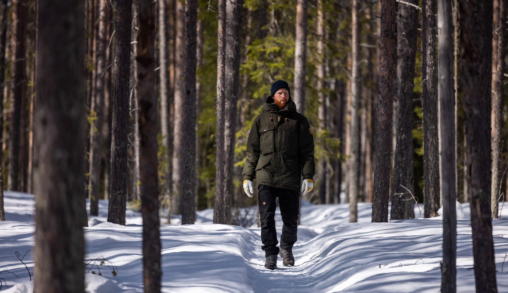 dik-bepakte man loopt door besneeuwd bos