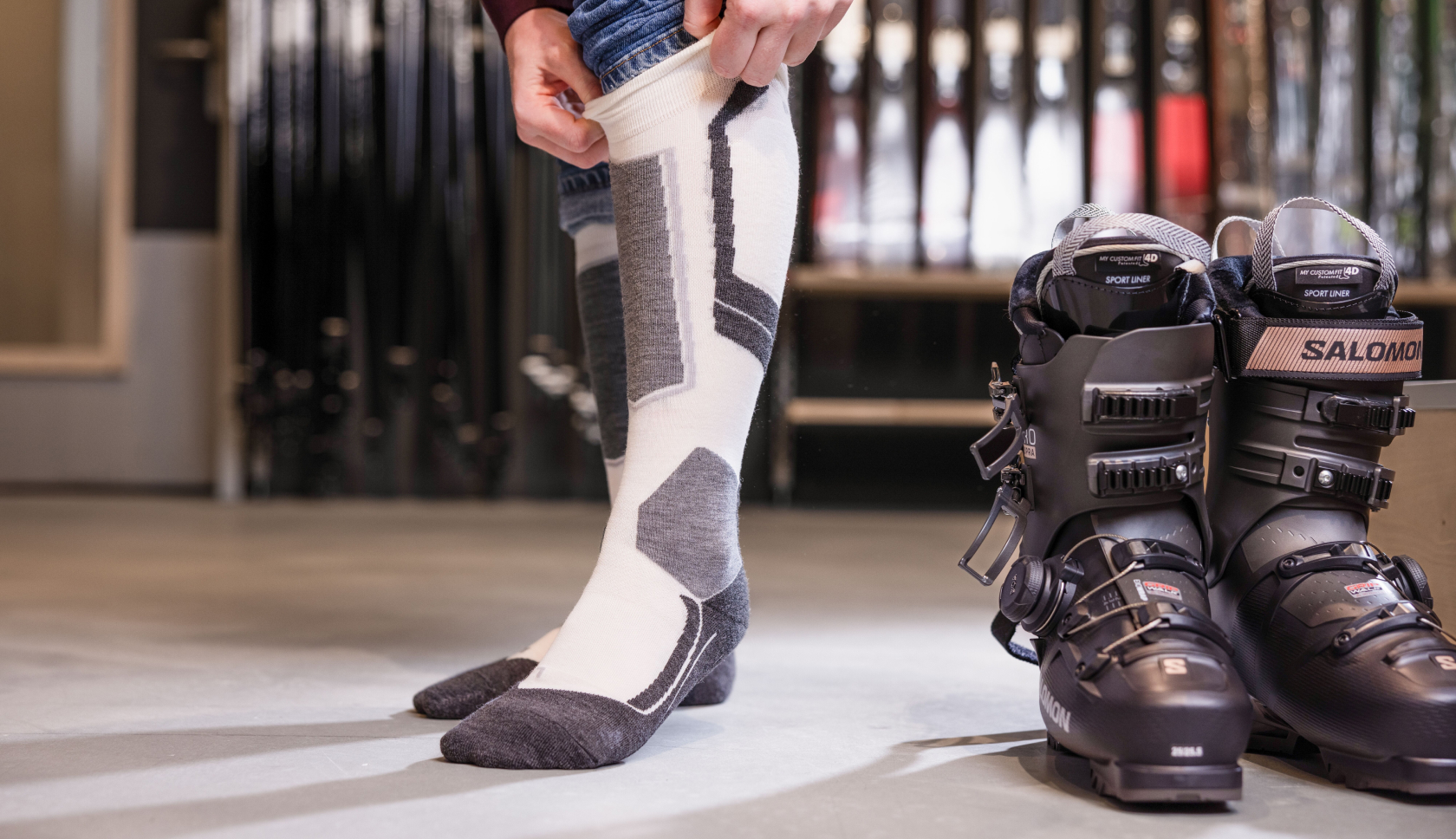 persoon trekt sokken aan naast skischoen in de winkel