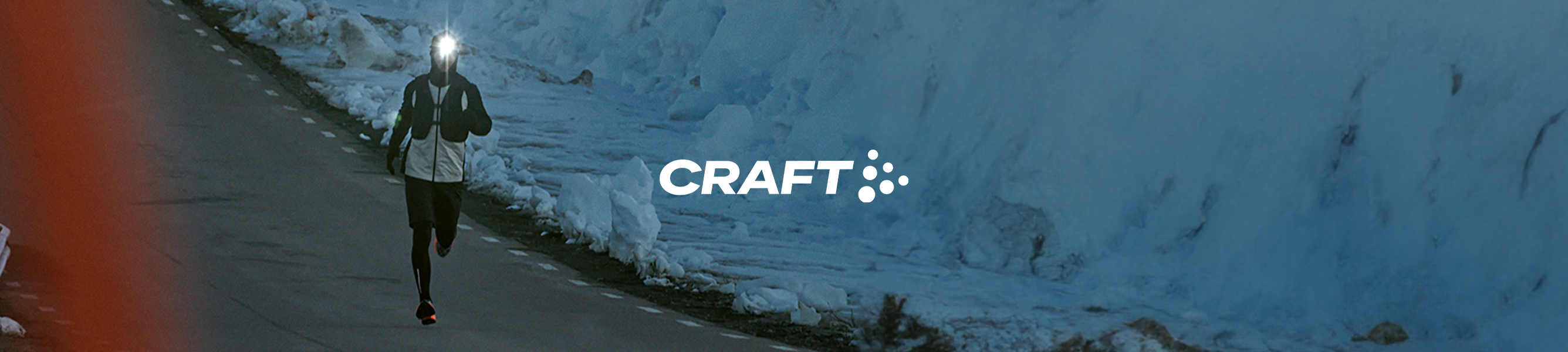 hardloper met hoofdlamp rent in het donker over snelweg naast besneeuwde berg