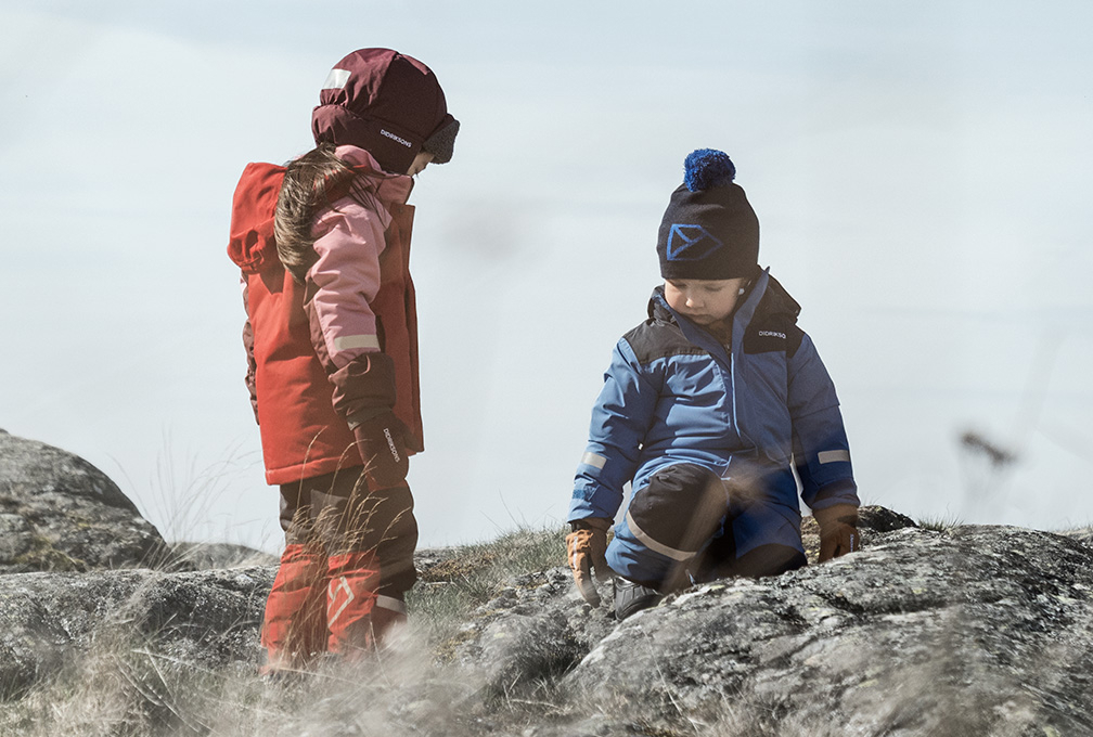 twee peuters in winterkleding op een rots