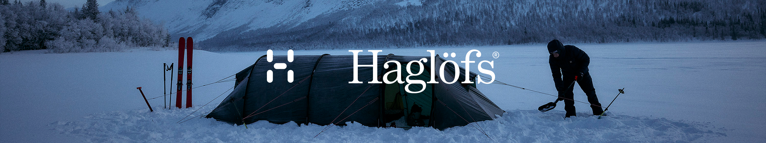 man in dikke winterkleding zet tent op in de sneeuw