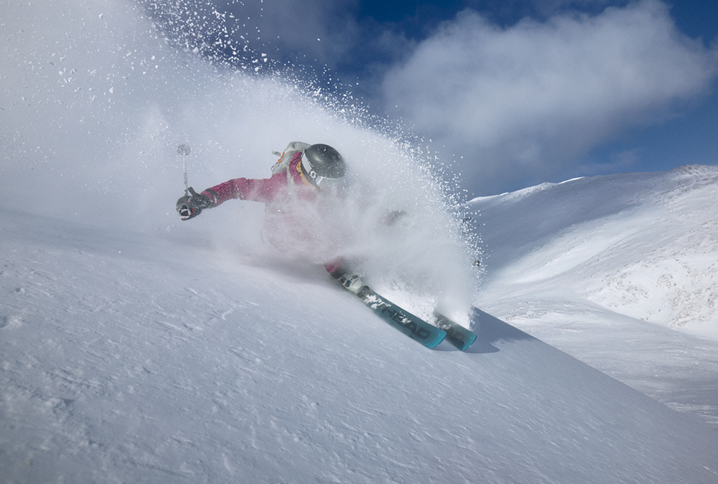 vrouw skiet naar beneden terwijl de sneeuw omhoog spat
