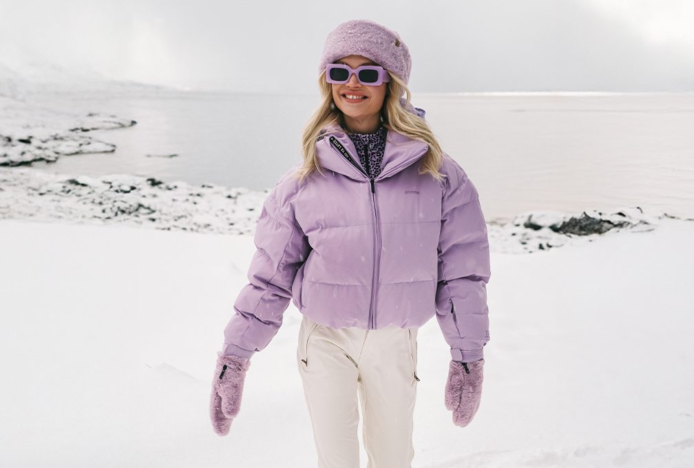 vrouw in paarse jas loopt door de sneeuw