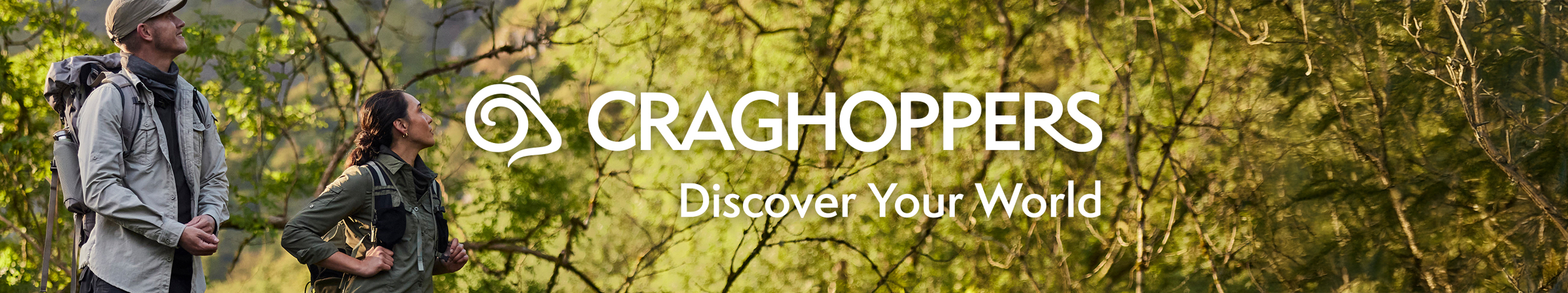 Een man en een vrouw met een rugzak om kijken omhoog in een bos.