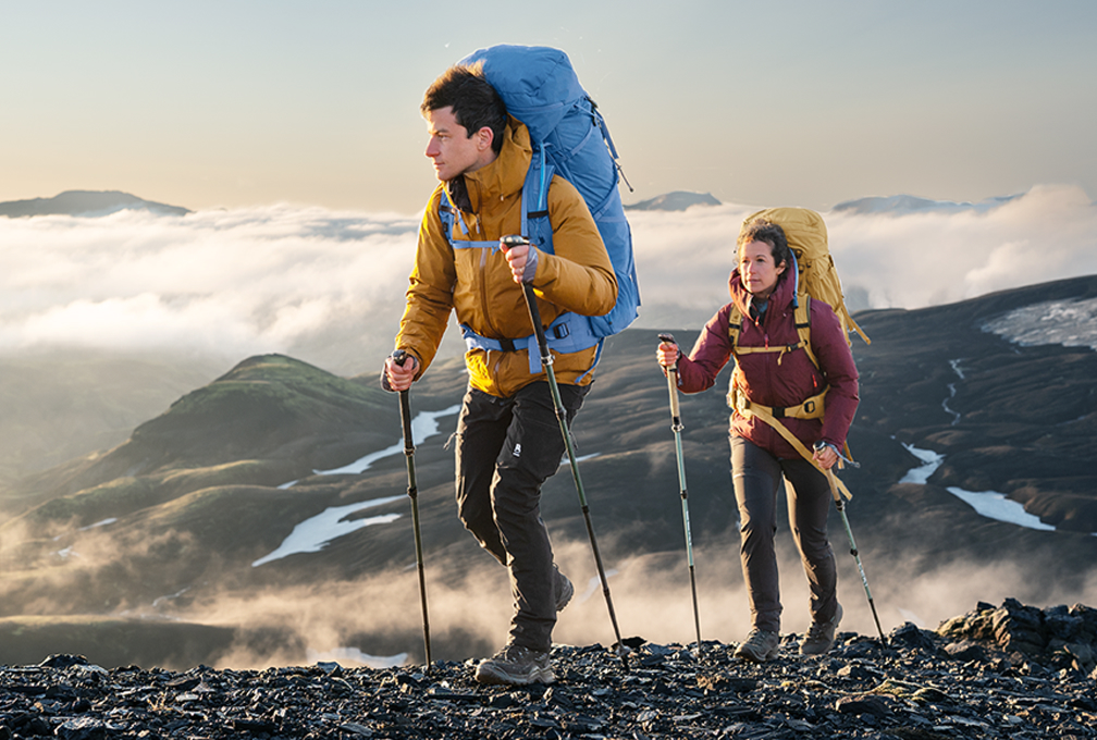 Twee mensen wandelen door de bergen met grote rugzakken om.